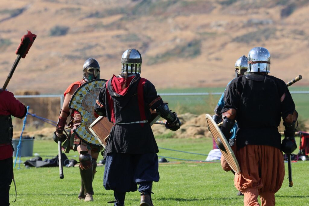 Four armored fighters are facing each other on a grassy field.
